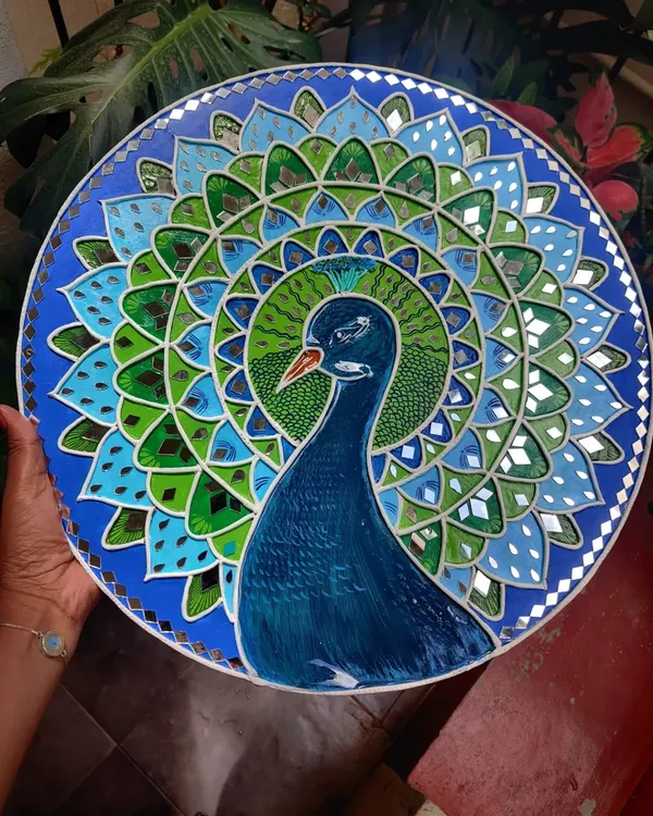A close up of my 17 inch peacock Lippan art on a wooden board. The vibrant blues and greens, combined with the shimmer of mirror work, capture the grace of our national bird.