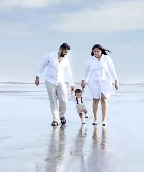 A beautiful family portrait taken during an outdoor session on the beach. The coordinated white outfits and the natural, expansive background create a serene and classic image of family togetherness.