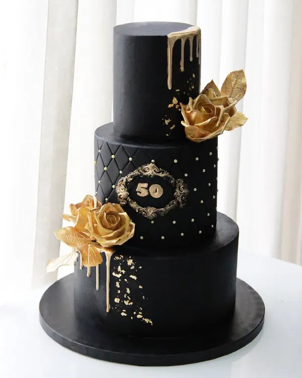 A 50th birthday deserves a statement piece. This dramatic three-tiered black and gold cake features a quilted middle tier, a custom monogram, and beautiful golden sugar roses.