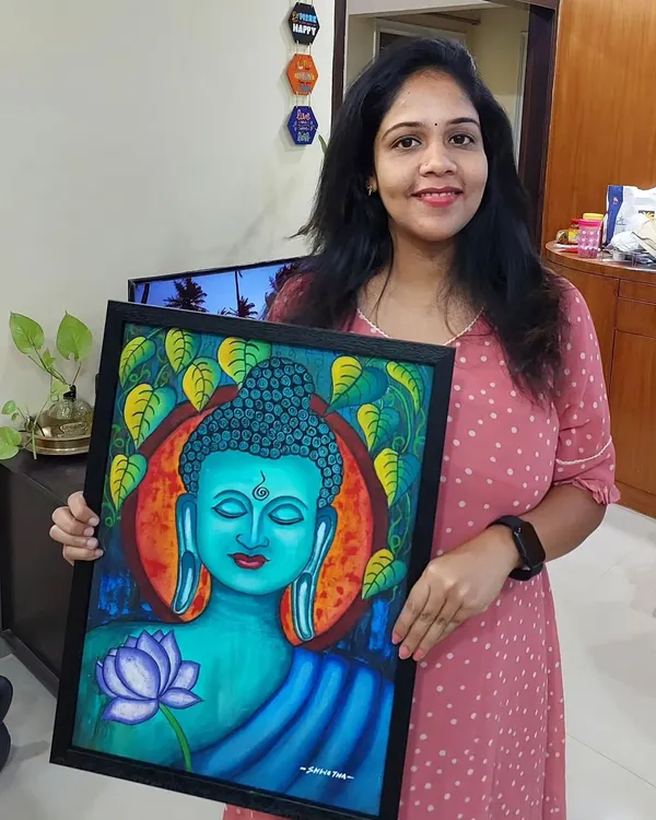 Here I am, holding a finished Buddha painting with a vibrant blue and orange background. The Bodhi leaves and lotus flower add to the serene feeling.