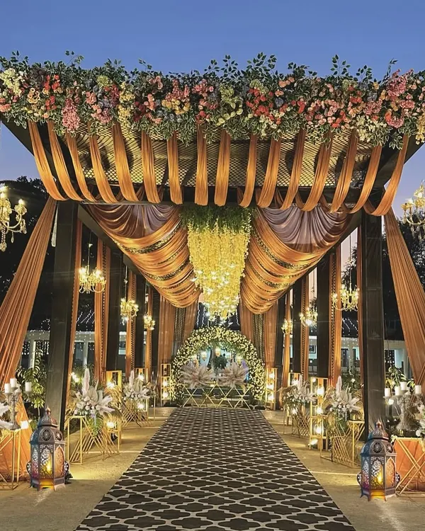 I believe the first impression sets the tone for the entire celebration. This grand floral entrance was designed to make guests feel like they were stepping into a fairytale, with a canopy of flowers, draped fabrics, and elegant chandeliers lighting the way to the main event.