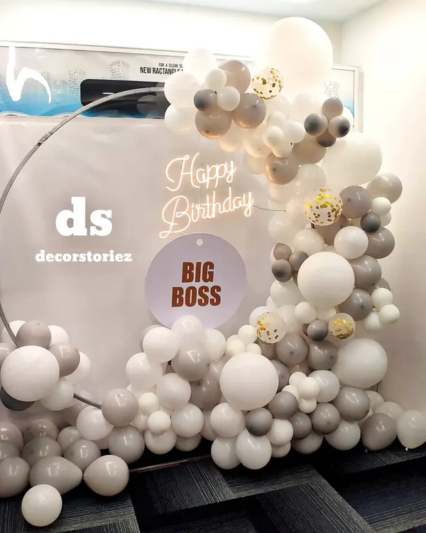 We created this modern photo backdrop for a boss's birthday celebration. The setup features a sophisticated palette of white and grey balloons on a metal ring frame, a custom 'BIG BOSS' sign, and a warm 'Happy Birthday' neon light to complete the look.