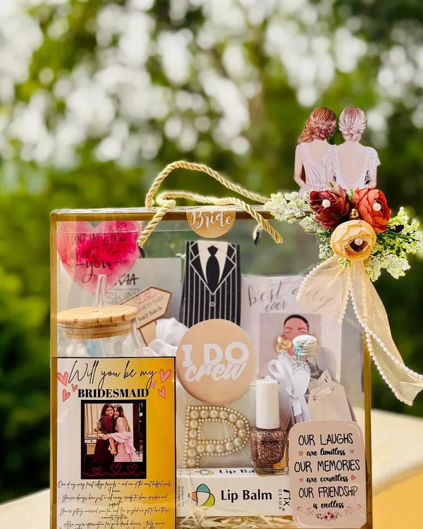This "Will you be my bridesmaid?" proposal box is a beautiful way to ask your best friends to be part of your bride tribe. It's a transparent bag filled with personalized goodies like a custom wine glass, initial pin, and a photo card.