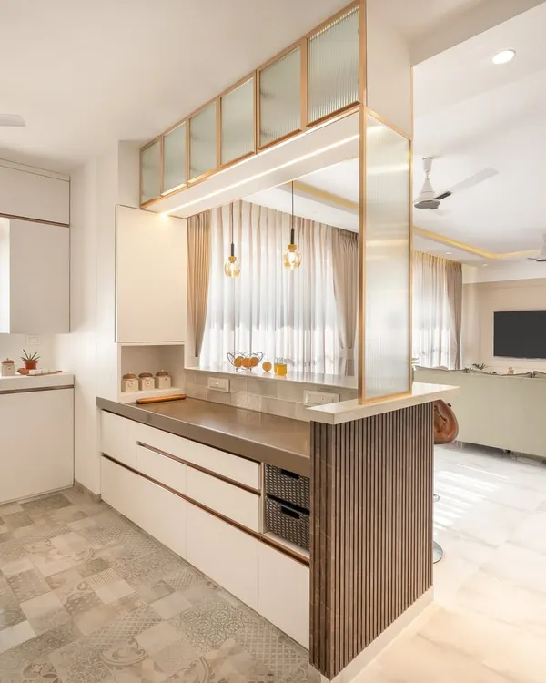 This open-concept kitchen features a breakfast bar that separates it from the living area while keeping the space connected. We used white handle-less cabinets, a dark countertop, and fluted glass overhead units to create a look that is modern, clean, and functional.