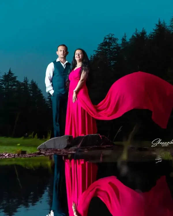 A dramatic pre-wedding shot by a lake at dusk. The flowing dress and its reflection in the water create a stunning, artistic image that tells a romantic story.