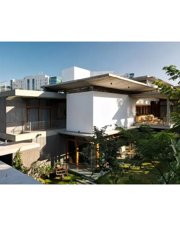 An exterior view showing the layered composition of concrete slabs and white volumes, nestled within the landscape.