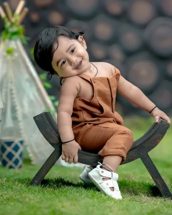 What a sweet pose! This little one looks so adorable in our garden, sitting on a rustic wooden bench with a teepee in the background.