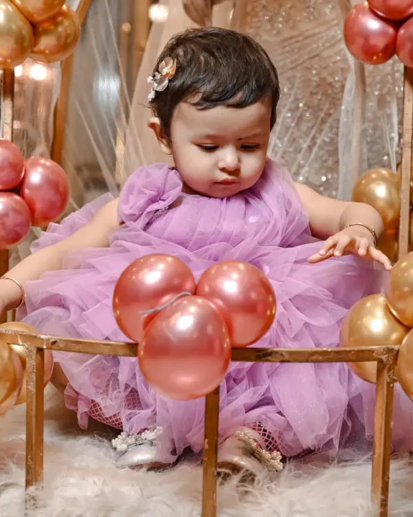 Capturing the curiosity of a one year old. This little girl is exploring her beautiful birthday setup, complete with pink and gold balloons.