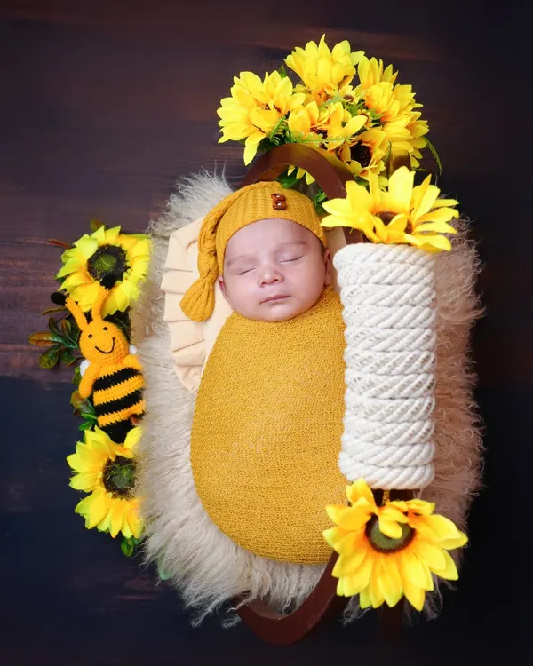 A sweet "bumbblebee" themed shoot with a baby in a yellow wrap, surrounded by sunflowers and a cute toy bee. This setup is bright, cheerful, and perfect for a sunny disposition.