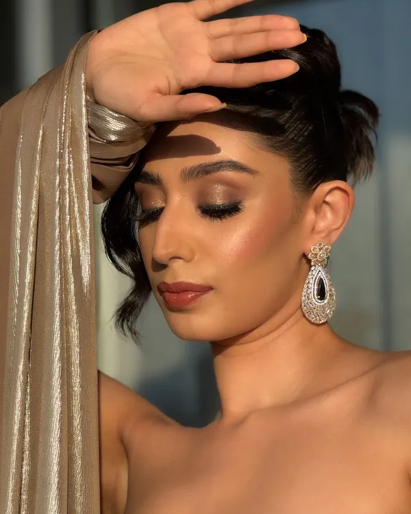 This is the epitome of cocktail glam meeting golden hour. The warm, bronzy tones on the eyes and the radiant highlighter on the cheeks are designed to catch the sunset light perfectly.