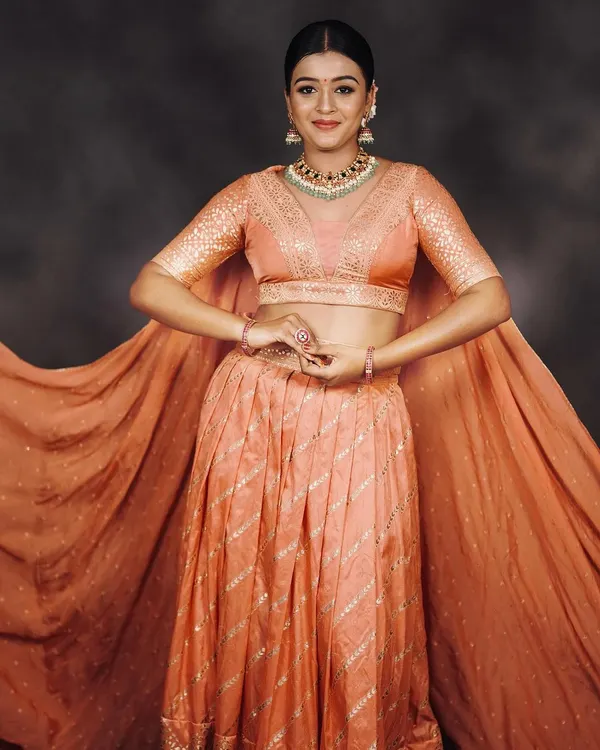 A graceful peach lehenga with cape-style sleeves. This outfit is light, elegant, and perfect for a sangeet, reception, or bridesmaid look.