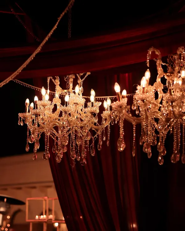 Crystal chandeliers hanging against rich, red velvet drapes. This combination of textures and the warm, sparkling light created an atmosphere of pure opulence and romance for this sundowner wedding.