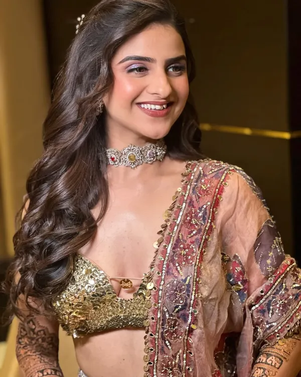 Mehandi, but make it couture. This look is about luxury without excess, featuring a flawless base, shimmering lilac eyeshadow, and soft curls to complement a high-fashion lehenga.