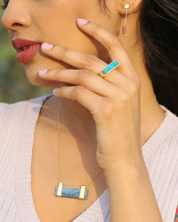A lifestyle jewelry photograph showing a model wearing a matching gemstone necklace and ring set. This style of on-model photography helps customers visualize how accessories look in a real-world context.