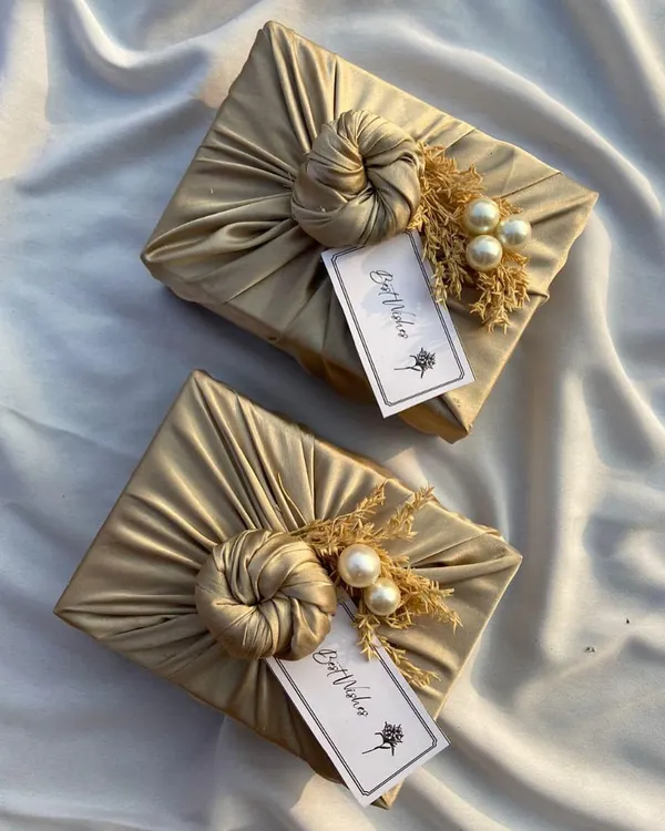 Part of my 'It's a wrap' series. These gifts are wrapped in golden satin fabric using the Furoshiki technique, adorned with dried flowers and pearls for an elegant, rustic look.