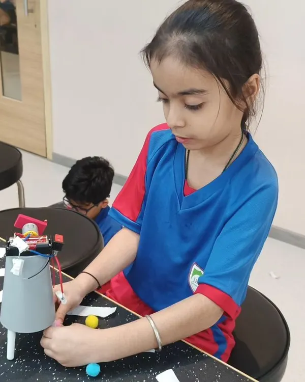 A young engineer focuses intently on assembling her robot. Each session encourages logical reasoning and provides hands-on building experience.