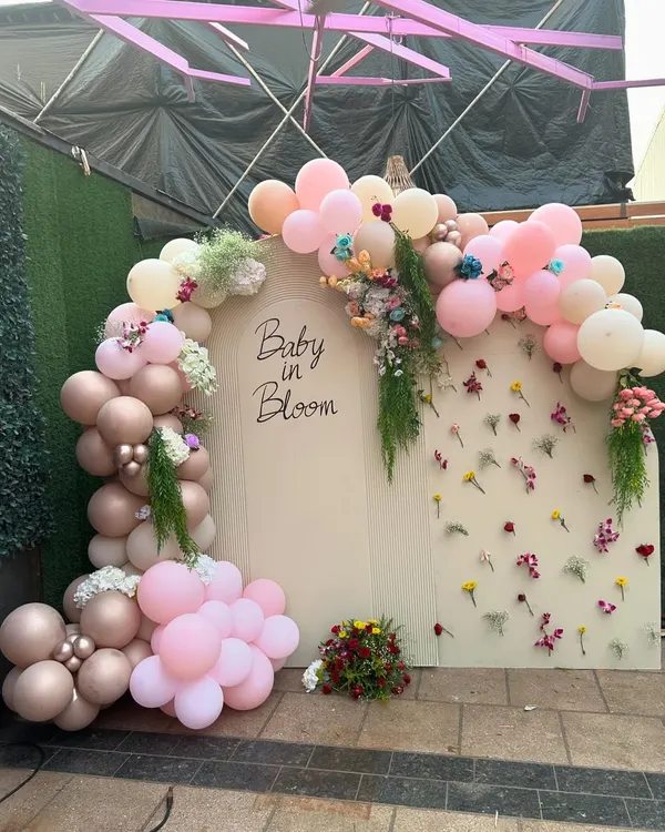 A 'Baby in Bloom' backdrop designed for a Godh Bharai ceremony, combining a modern balloon arch with a wall of delicate, individually placed flowers.