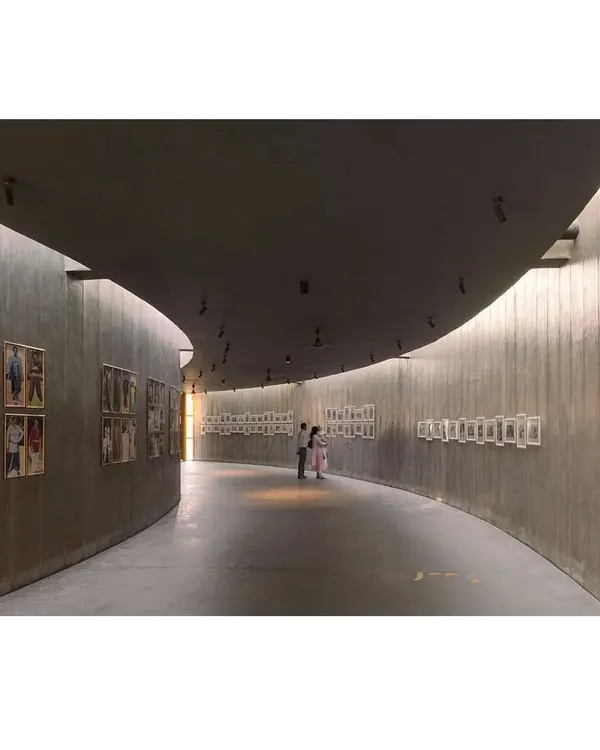 For the Dr. Vishnuvardhan Memorial, I designed this curved gallery wall to guide visitors on a journey through the actor's life. The raw concrete walls and soft, indirect lighting create a contemplative and reverent atmosphere for the exhibition.