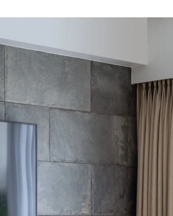 A detail shot showing the clean lines where the slate stone wall meets the ceiling. This precision and attention to architectural detail is a hallmark of our work.