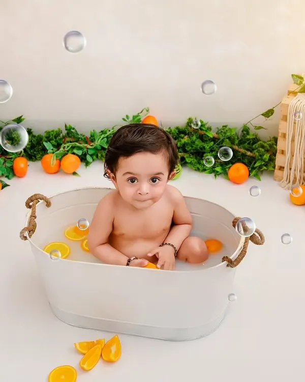 It's summertime. This little one is having a splash in a tub full of oranges and bubbles, a perfect way to capture a fun milestone.