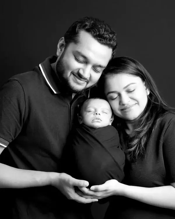 A serene black and white portrait of parents lovingly holding their swaddled newborn. Our studio sessions provide a calm and controlled setting, perfect for creating peaceful newborn family photos.