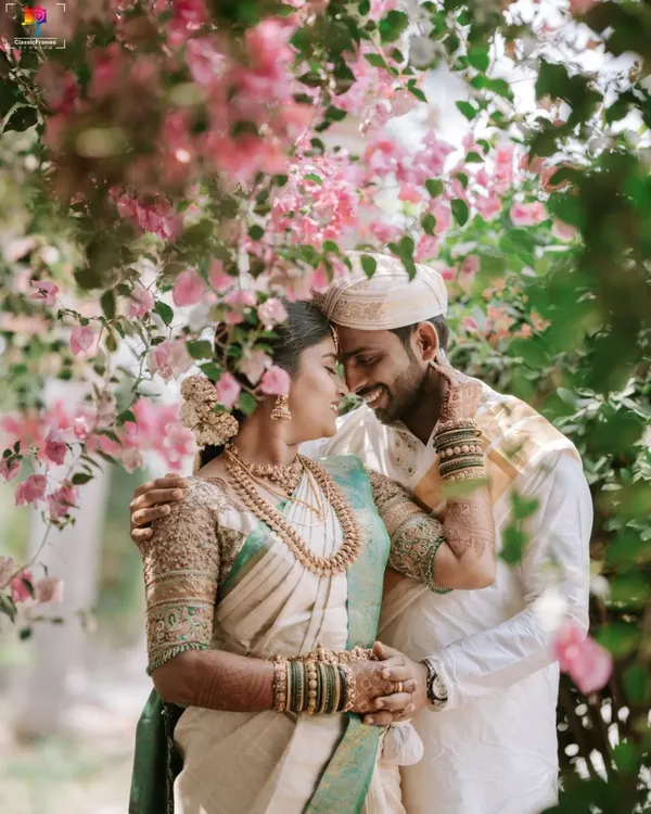 A tender moment shared between the couple, framed by beautiful pink bougainvillea. This style of natural, romantic portraiture is perfect for capturing the soft emotions of your South Indian wedding day.