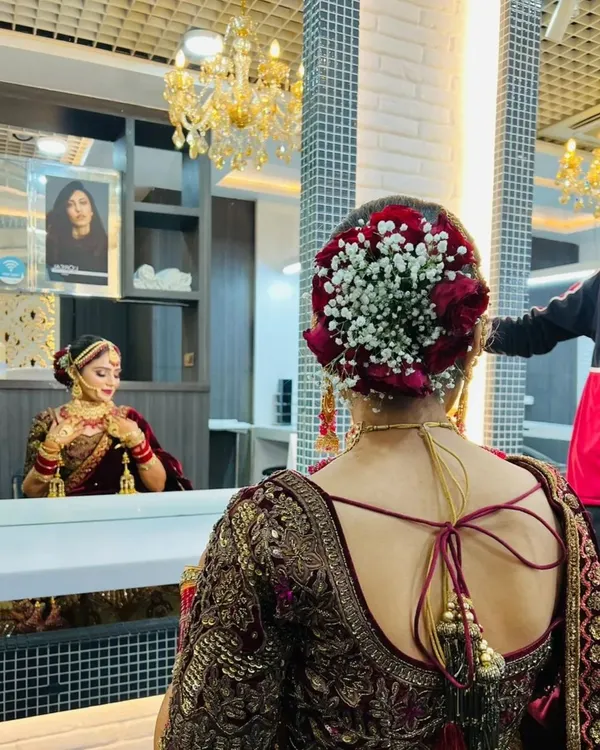 A close-up of a classic bridal hair bun. This intricate style is adorned with a combination of red roses and delicate gajra, perfect for a traditional wedding ceremony.