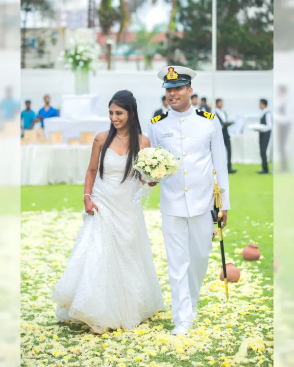 A beautiful Christian wedding procession, with the bride in a stunning white gown and the groom in his naval uniform, walking down an aisle of petals.