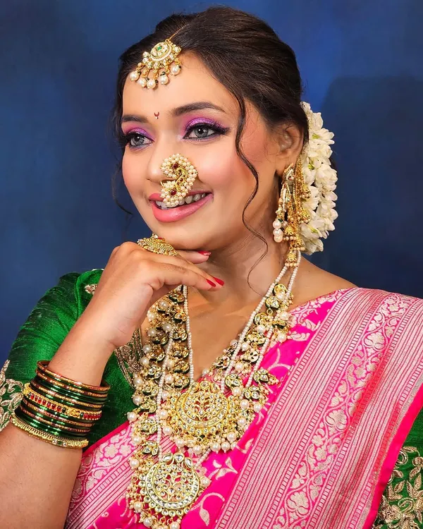A radiant Maharashtrian bride, embodying grace and tradition. I created this look with vibrant pink eyeshadow to match her saree and a classic nath that completes the look.