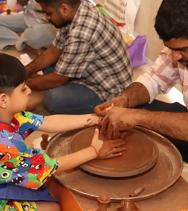 An instructor guides a child's hands as they learn to center clay on the pottery wheel. It's a wonderful sensory activity that teaches physics in a creative way.