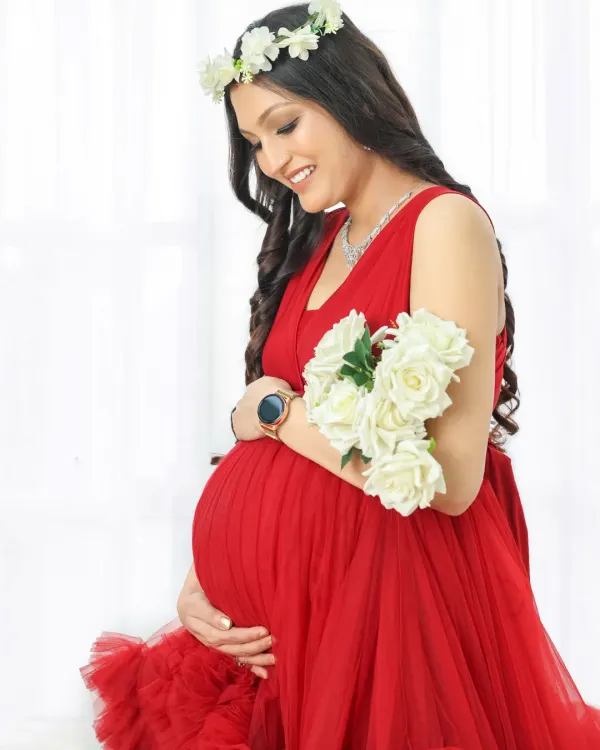 A classic solo maternity portrait. The vibrant red gown, floral crown, and soft smile perfectly capture the joyful glow of a mom-to-be.
