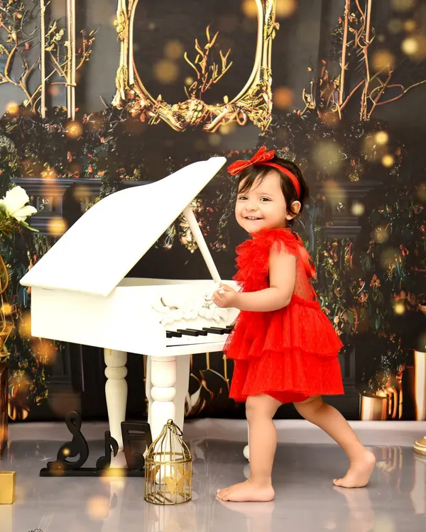 A candid moment at the piano. Dressed in a vibrant red dress, she creates her own sweet melody in this elegant, musically-inspired photoshoot.