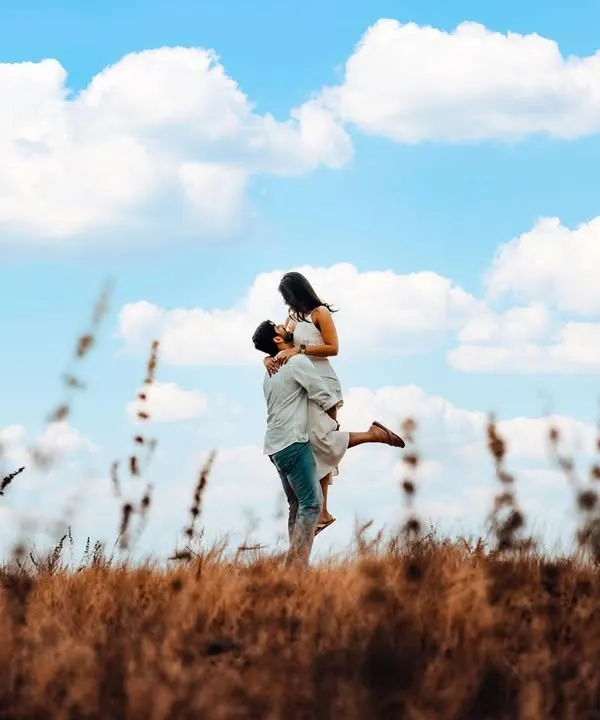 A classic romantic lift against a bright blue sky, capturing a feeling of pure joy and freedom. This outdoor pre-wedding shot showcases our love for wide, scenic compositions.
