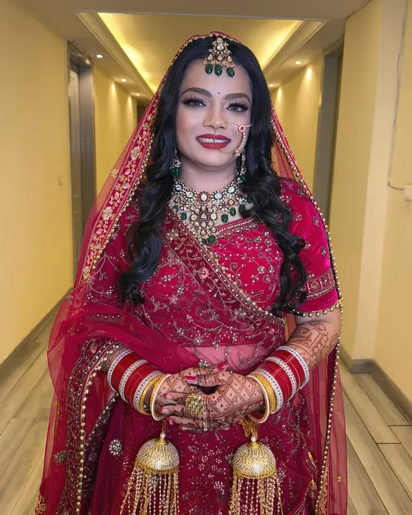 A full portrait of our beautiful bride who chose an open hairstyle for her D-Day. The classic red lehenga and bold lip create a timeless wedding look.