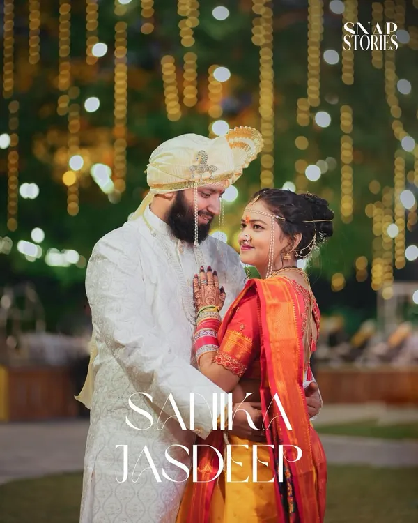 A beautiful evening portrait of a Maharashtrian couple, with the warm glow of decorative lights creating a magical bokeh effect. We excel at using ambient light to create romantic wedding photos.