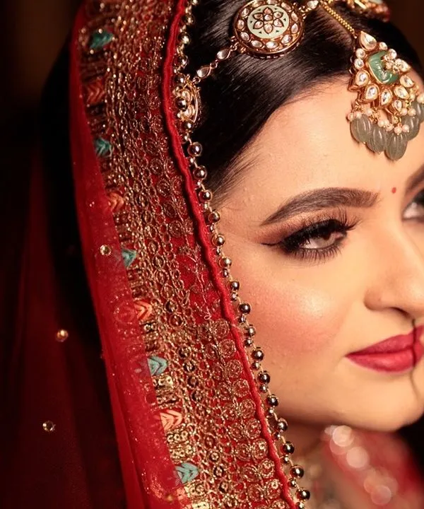 A close-up of our stunning bride. I focused on creating sharp, winged eyeliner and bold red lips to complement her traditional jewelry and create a look of pure royal elegance.