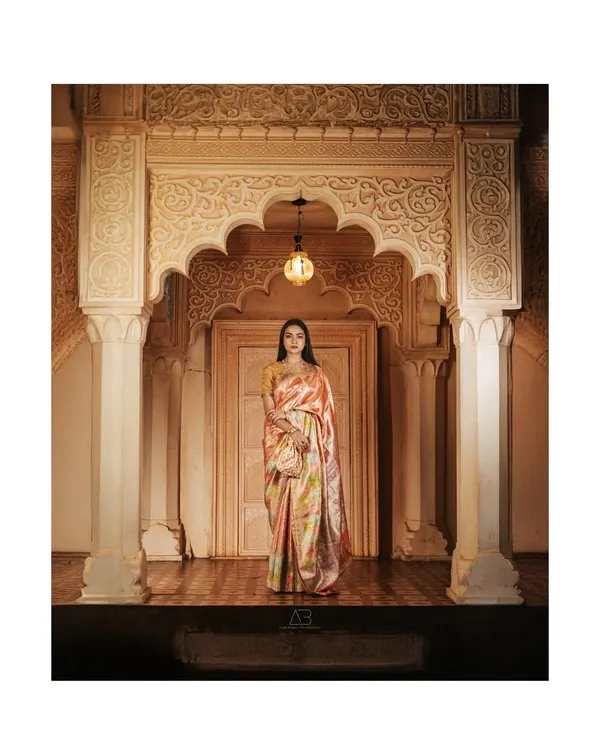 A full-length view from our iconic saree shoot, showcasing the entire ensemble against the magnificent, hand-carved archway. This wide shot establishes the scene and gives the garment a sense of place and grandeur.