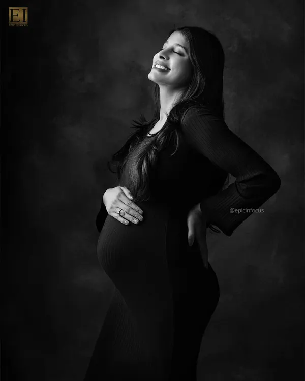 A portrait filled with pure joy, as the mom-to-be smiles with her eyes closed. The black and white format emphasizes her radiant expression.
