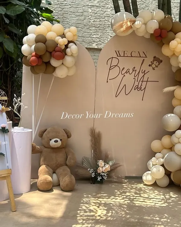 A modern and chic "We Can Bearly Wait" teddy bear themed baby shower. This setup features arched backdrops, a neutral-toned balloon garland, and a cute welcome board.