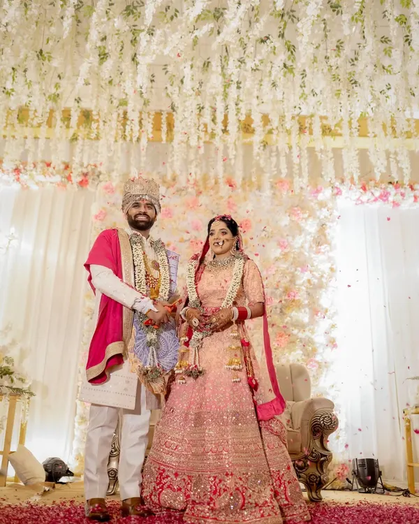 A beautiful portrait of the newly married couple during their Jaimala ceremony. They stand amidst a shower of flower petals under a stunning floral mandap, marking the beginning of their journey together.