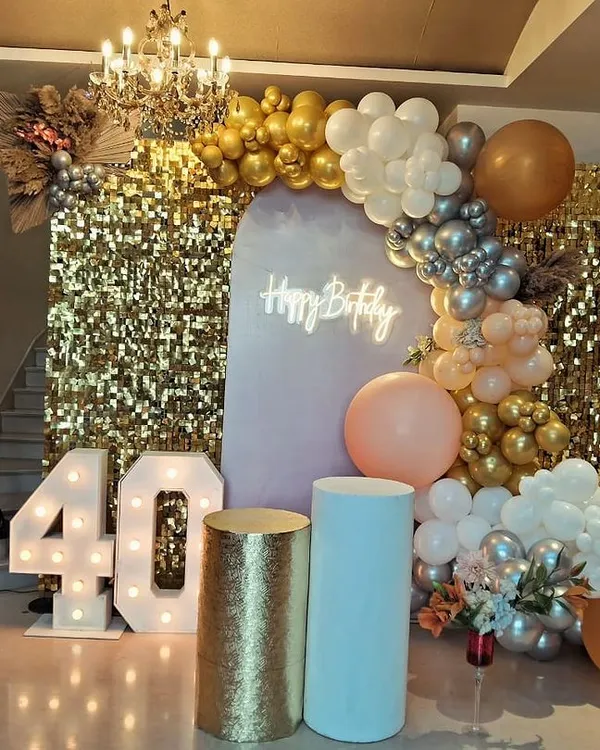 This is how we do 40 and fabulous. We transformed this space with a shimmering gold sequin wall, a custom "Happy Birthday" neon sign, and a dramatic balloon arch in gold, silver, and peach tones. The lit-up marquee numbers and elegant pedestals complete this luxurious look, perfect for a milestone celebration that deserves to be remembered.