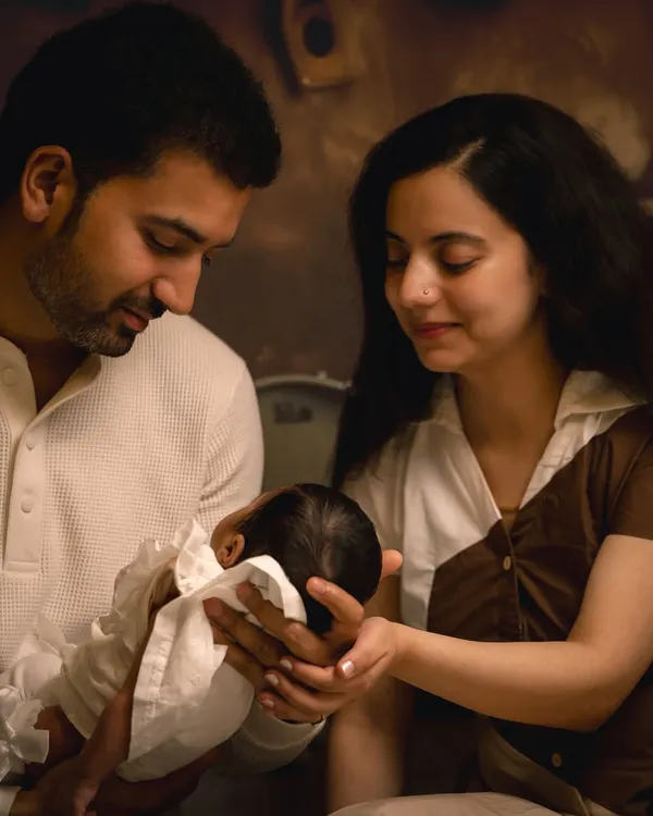 A classic family portrait with the parents gazing lovingly at their newborn. I guide families into natural poses that feel authentic and highlight their bond during these precious first days.