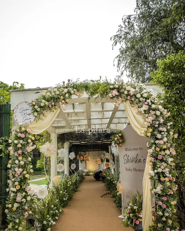 The entrance to our "Baby in Bloom" enchanted garden baby shower. A beautiful white pergola was draped in soft fabric and adorned with a lush arch of pink and white roses, setting a dreamy tone from the start.