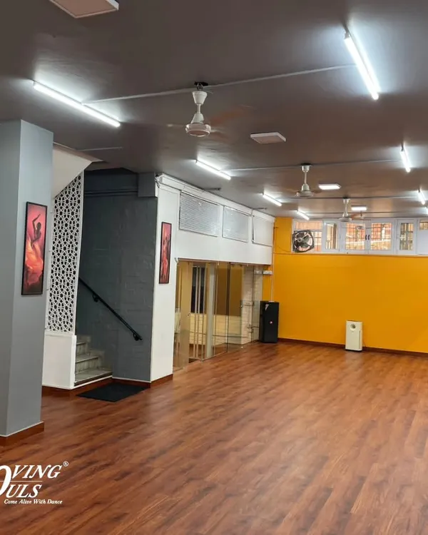 A wide view of our spacious studio with its bright yellow wall and professional dance floor. This is where the magic happens.