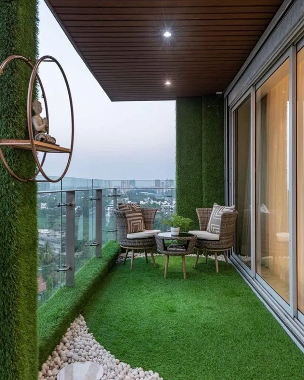 A modern high-rise balcony designed for serenity. We used artificial grass walls and flooring, a white pebble bed, and minimalist decor to create a peaceful zen corner with a stunning city view.