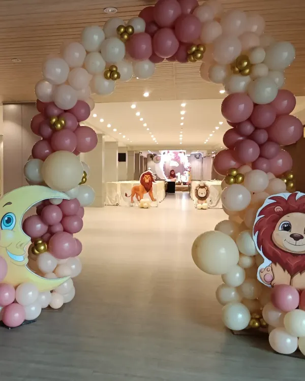 A grand entrance arch for a lion-themed party. This arch in dusty pink and cream colors, with cute moon and lion cutouts, welcomes guests into the celebration hall.