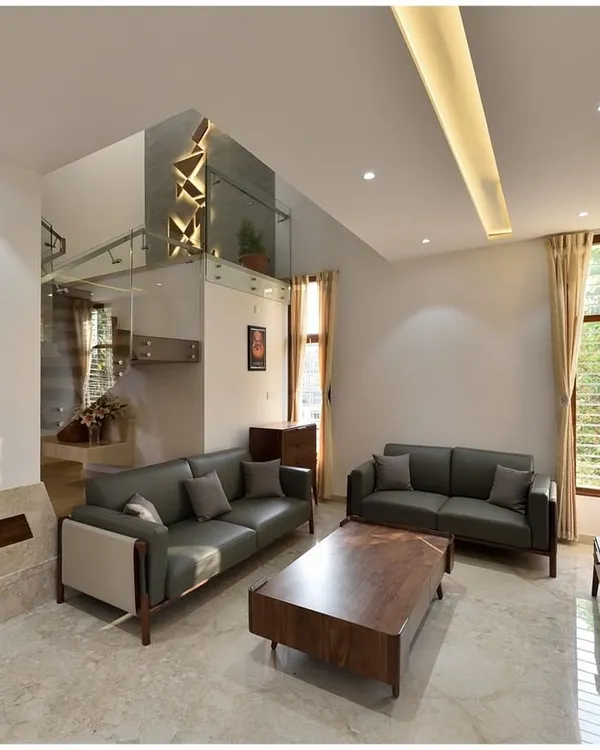 A modern living room in Mr. Ramu Siddappa's residence, where a double-height space above the staircase creates a sense of volume and connection between floors.