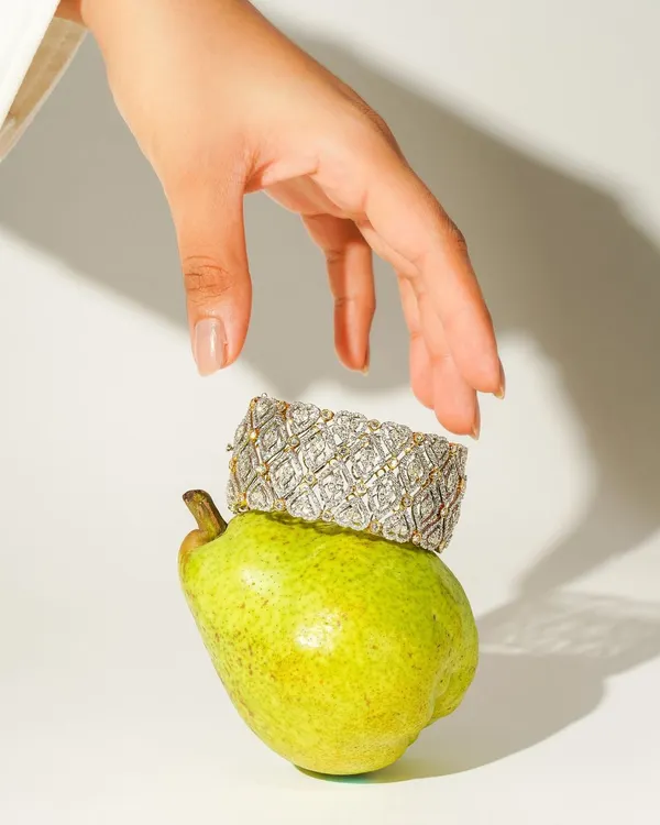 A creative and playful shot where a stunning diamond bracelet from Sarte Jewellery rests on a fresh pear. This unexpected pairing creates a memorable, artistic image that highlights the piece's unique design.