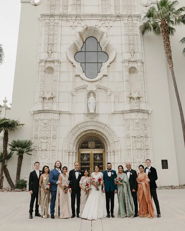 A grand family portrait outside the church, showcasing the complete, coordinated look for the Catholic wedding. From the bride's white gown and groom's teal tux to the family's attire in sage, rose gold, and navy, this is the culmination of our detailed wardrobe planning.