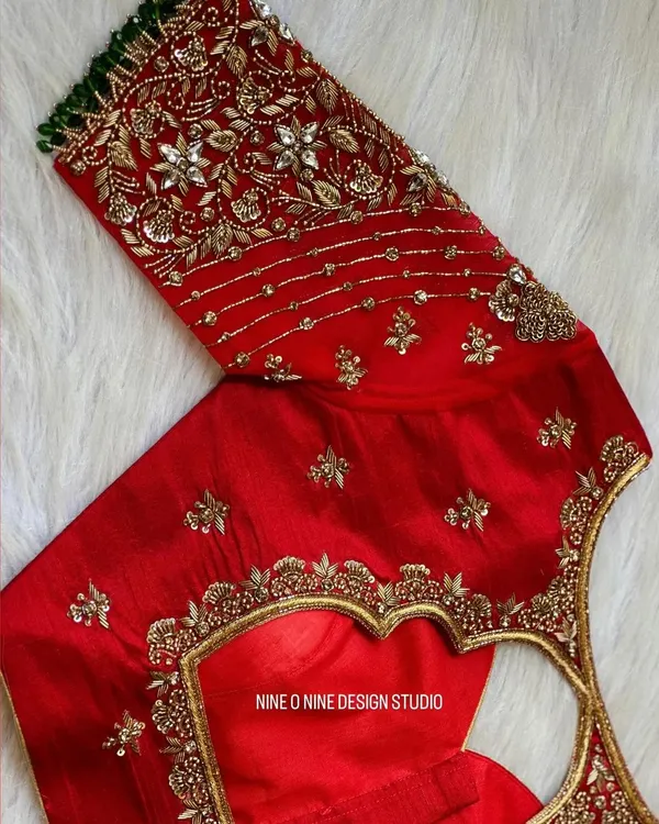 A masterpiece for our bride Madhuri. This classic red bridal blouse is heavily embroidered with zardosi and stone work, featuring a beautiful heart-shaped cutout on the back. The sleeves are a canvas of intricate floral patterns, making it a truly royal piece.